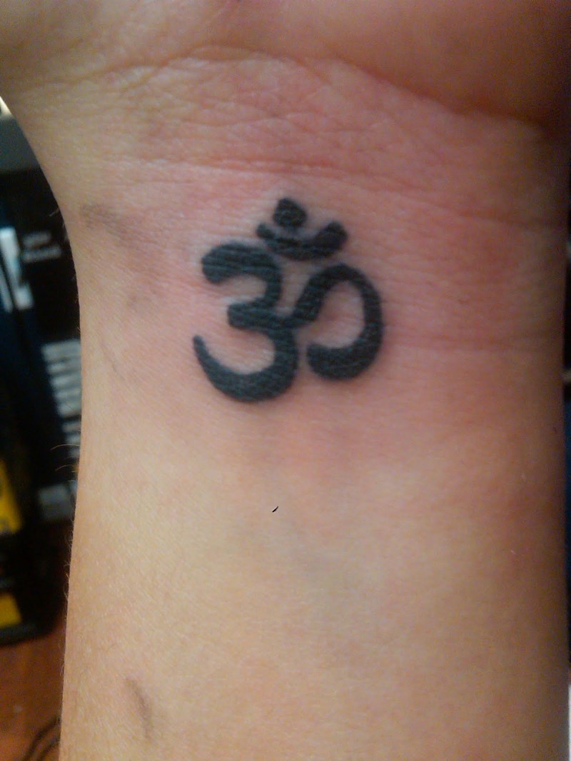 Black ink om symbol tattoo on wrist