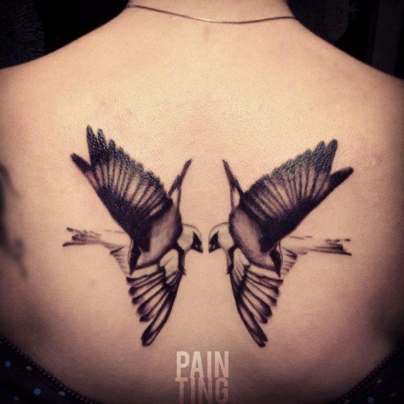 Black ink realistic looking black ink back tattoo of flying birds