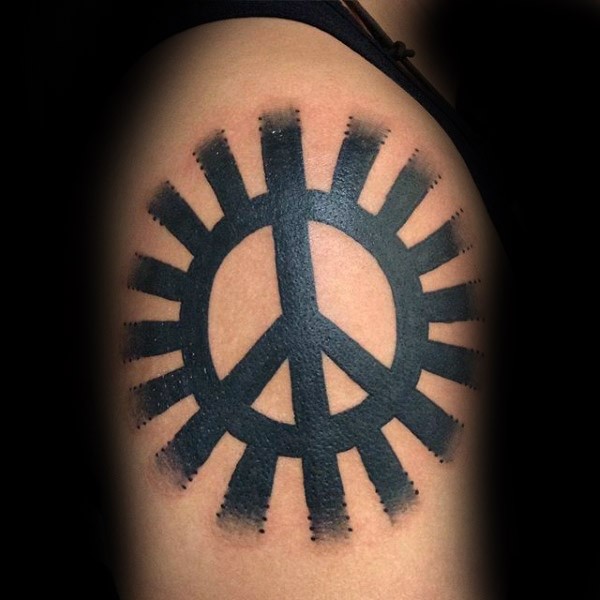 Black ink shoulder tattoo of pacific symbol with sun