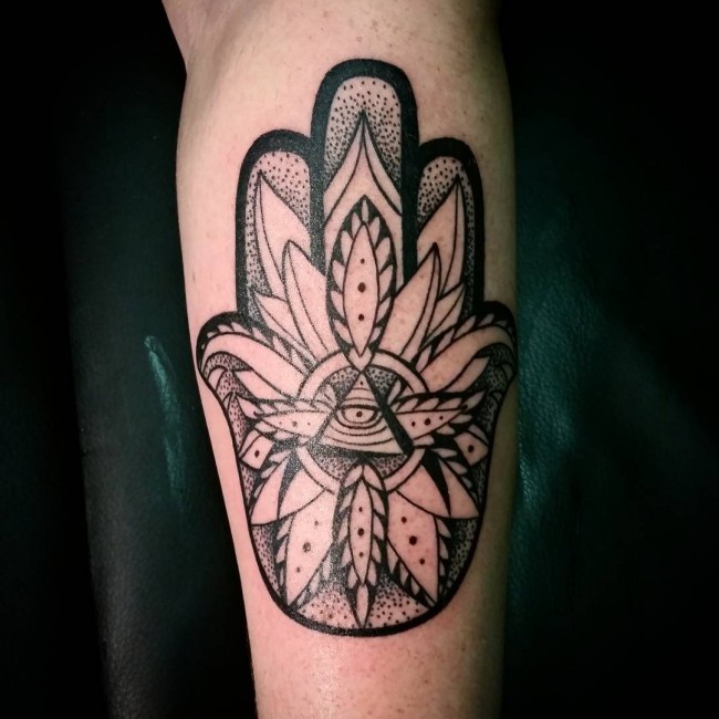 Black ink stippling style forearm tattoo of Hamsa symbol with leaves