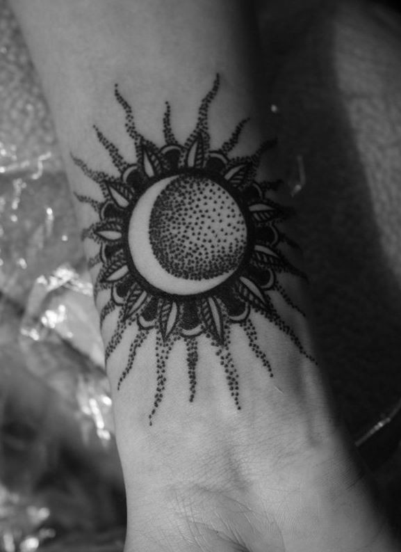 Black ink sun with moon tattoo on wrist