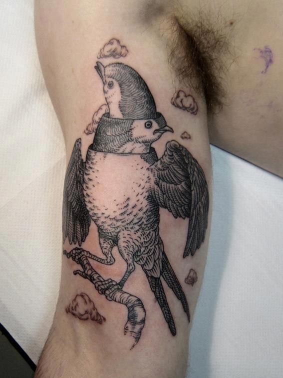 Black ink surrealism style biceps tattoo of interesting looking bird