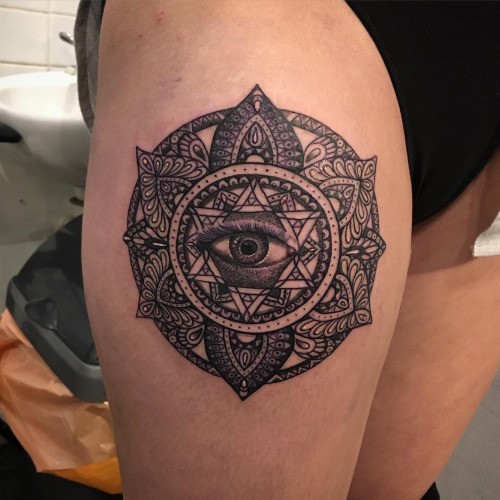 Black ink thigh tattoo of mystical eye with flowers