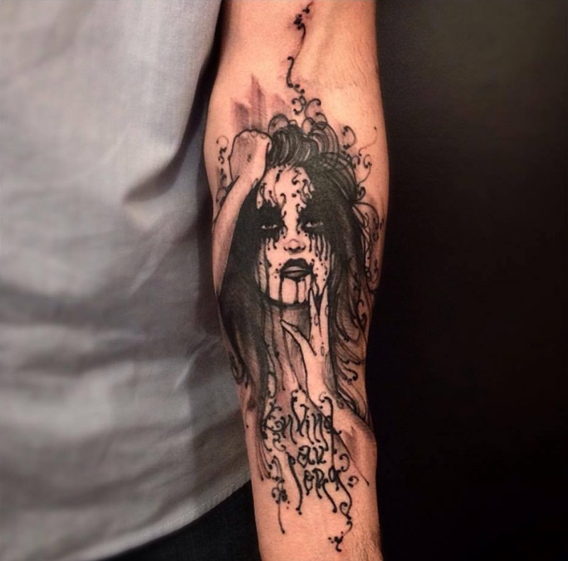 Black ink typical forearm tattoo of creepy woman with lettering