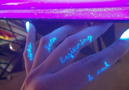 Black light scripts on fingers tattoo