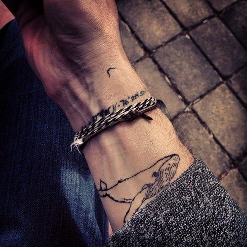 Black little whale tattoo on wrist