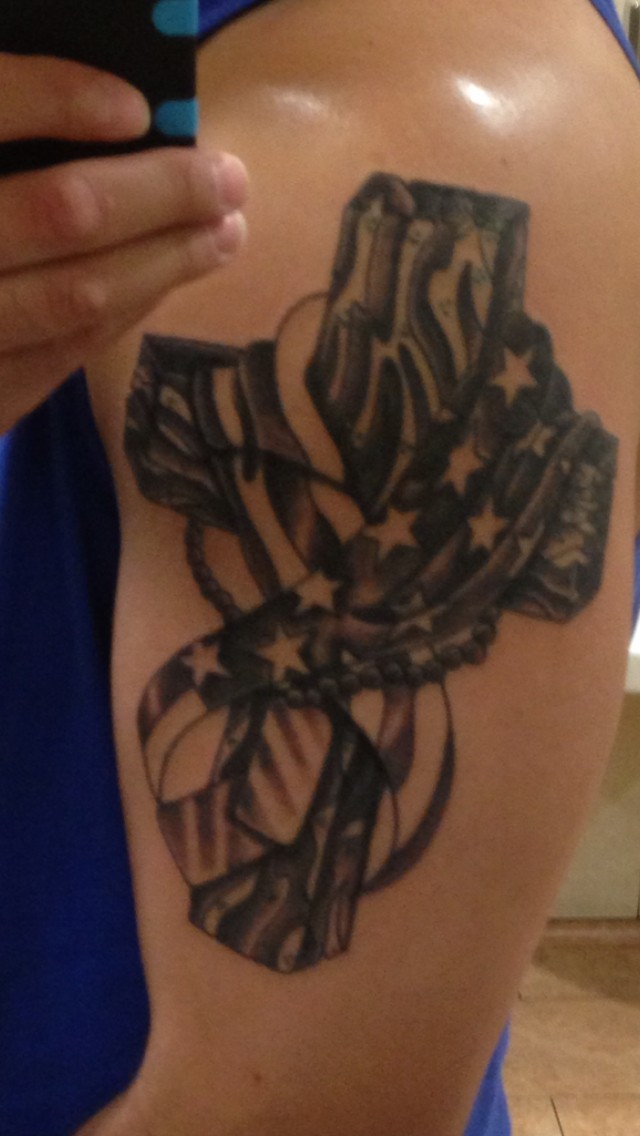 Tatuaje en el brazo de la cruz negra y la bandera en el memorial militar.