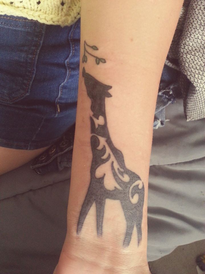 Black painted giraffe tattoo with branch