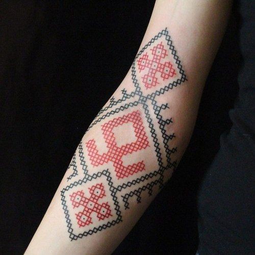 Tatuaje en el antebrazo, puntada de colores rojo y negro