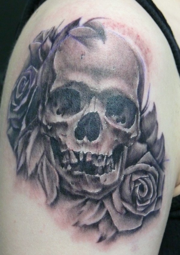 Tatuaggio sul deltoide il teschio tra le rose