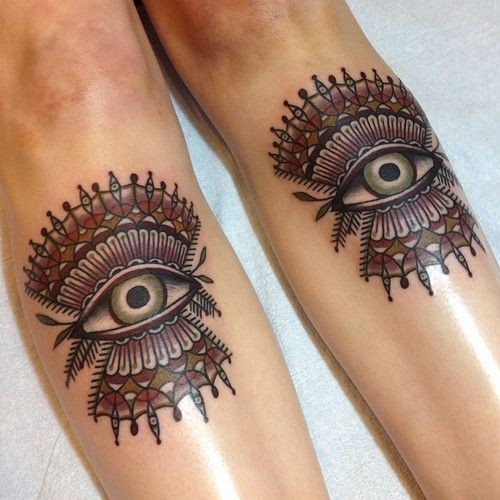 Black stylized eyes tattoo on legs