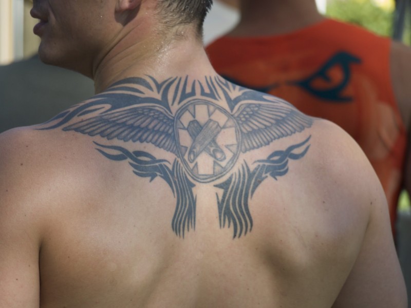 Black tribal wings tattoo on upper back