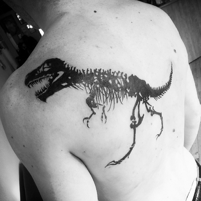 Blackwork style back tattoo of big dinosaur skeleton