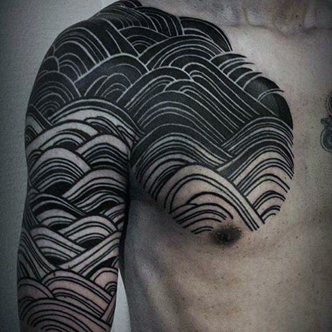 Blackwork style chest and shoulder tattoo of waves