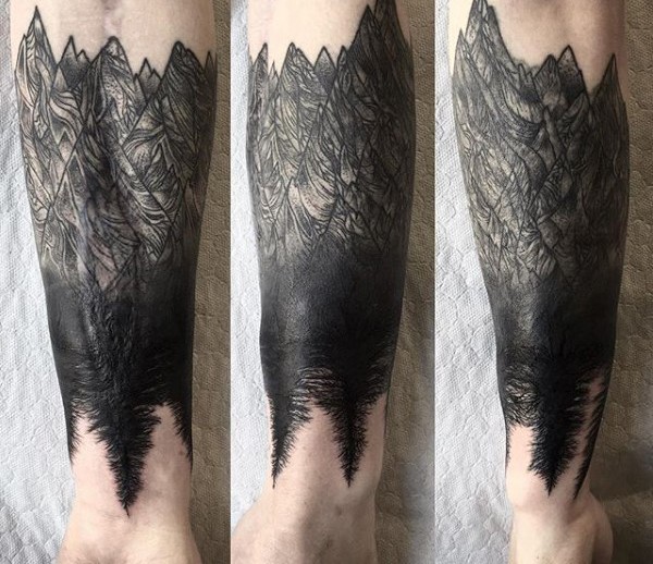 Blackwork style forearm tattoo of mountains with trees