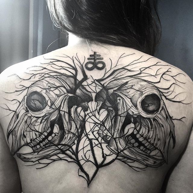 Blackwork Stil großes Tattoo am oberen Rücken mit mystischem Tierschädel und kleinen Symbolen