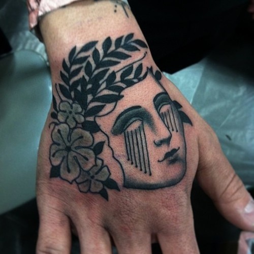 Blackwork style simple looking hand tattoo of woman head with flowers