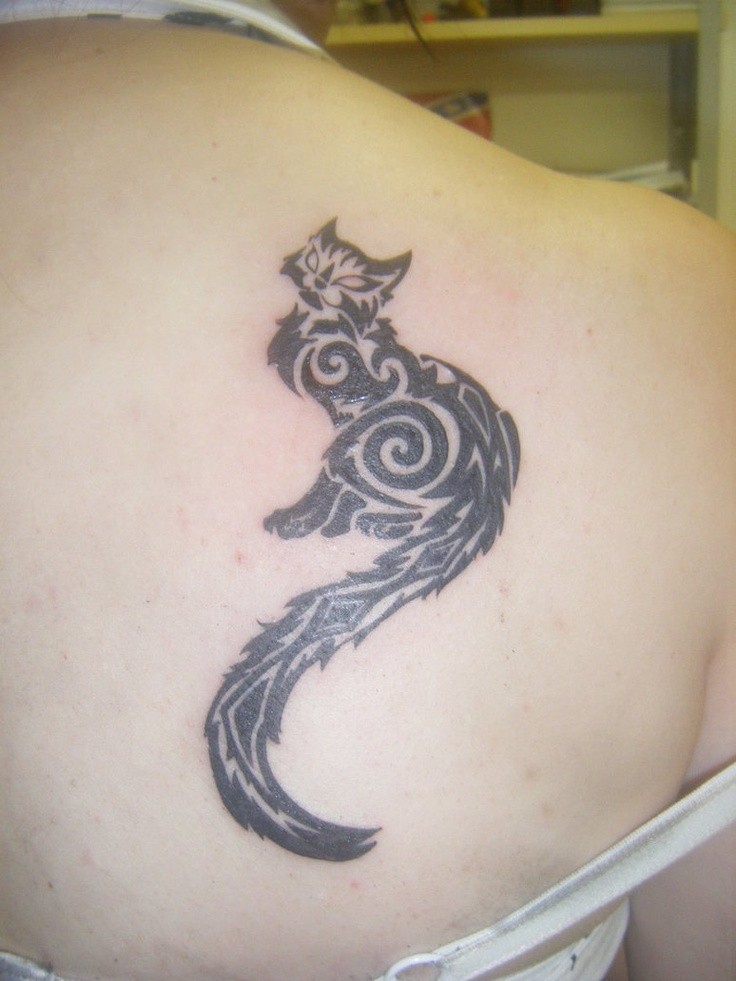 Black tribal cat with long tail tattoo on shoulder blade