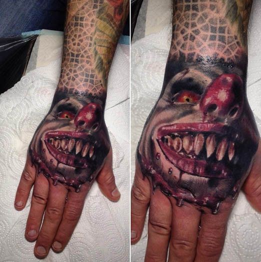 Bloody colored arm tattoo of creepy clown face