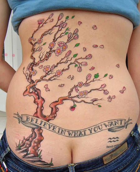 Blossoming cherry tree and inscription tattoo on back