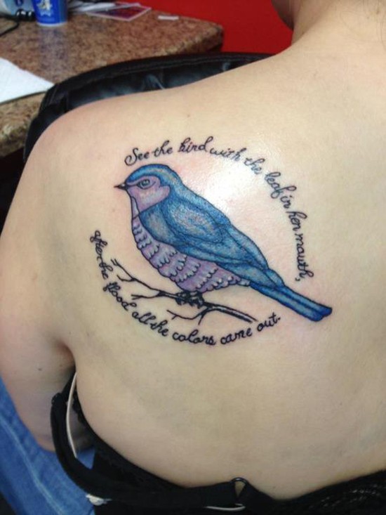 Tatuaje en el hombro, pájaro y inscripción en torno de él
