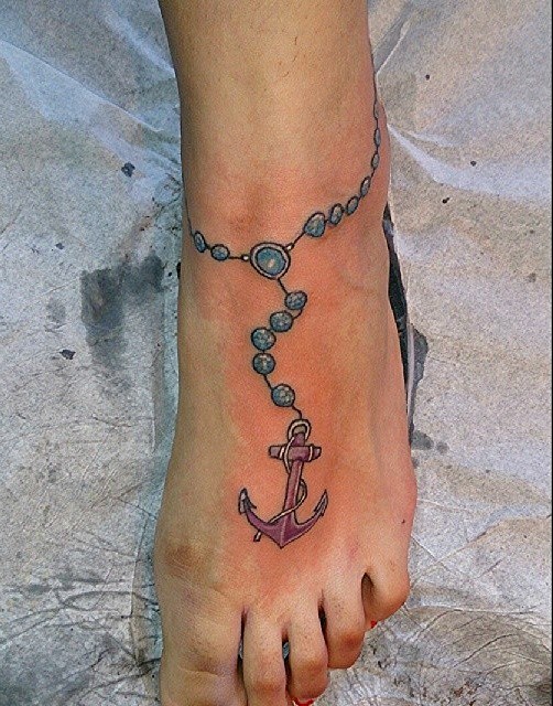Tatuaje en el tobillo, 
pulsera azul con ancla púrpura