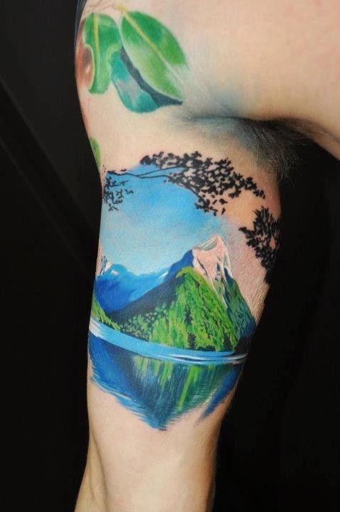 Breathtaking natural looking and colored big mountain lake tattoo on arm