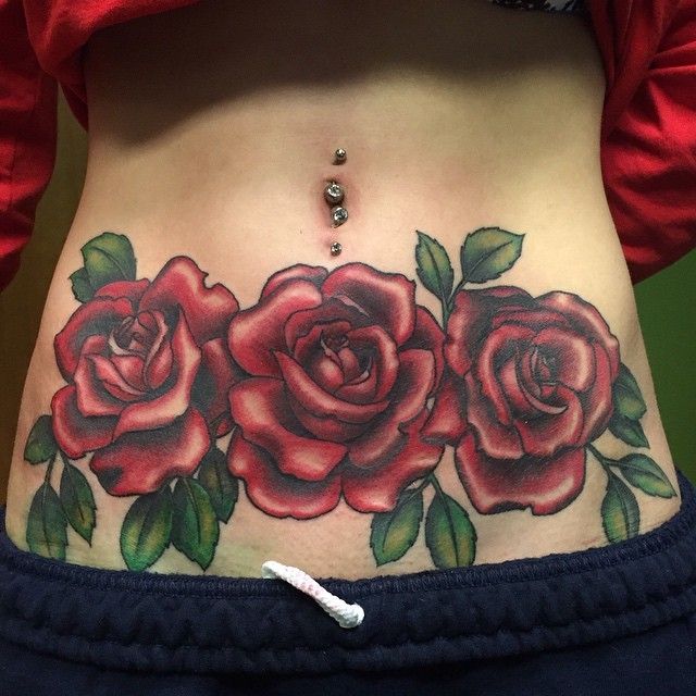 Bright three red rose flowers naturally colored tattoo on woman&quots belly in old school style
