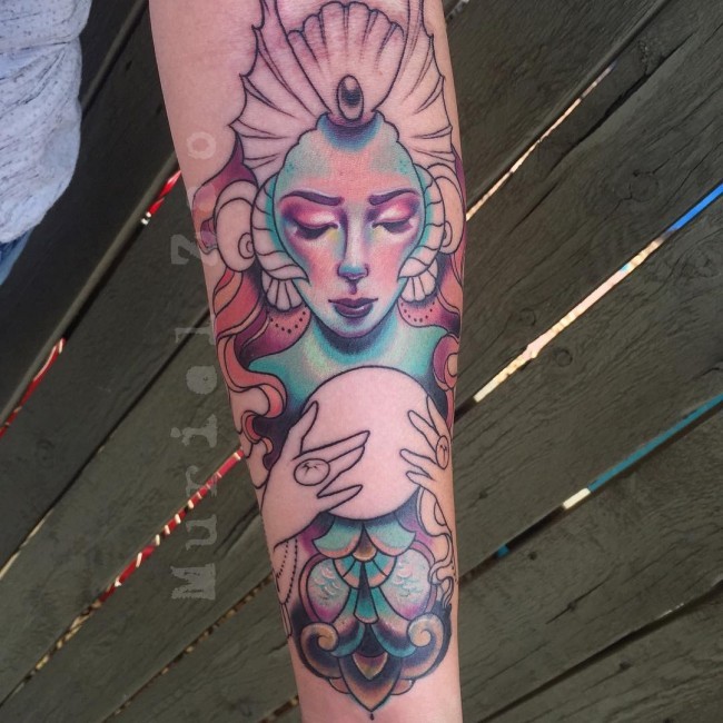 Brilliant designed and colored magical mermaid tattoo on forearm with magic orb