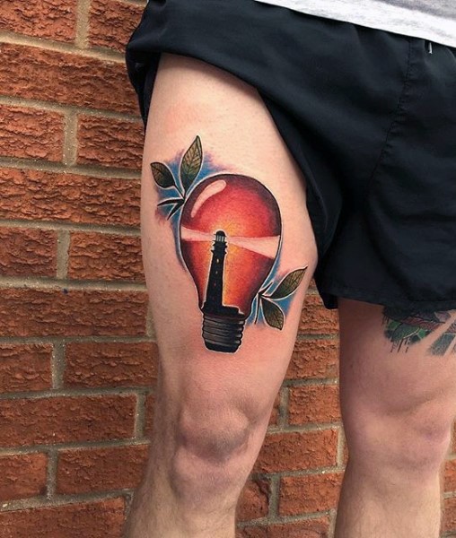 Bulb with lighthouse inside colored thigh tattoo with leaves and blue haze
