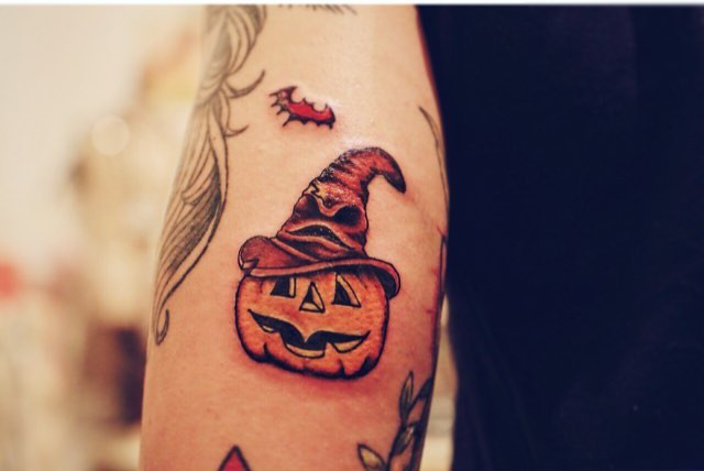Cartoon like tiny 3D magical pumpkin tattoo on arm with bat