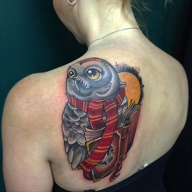 Cartoon style beautiful colored wise owl tattoo on back with book and moon
