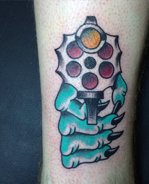 Cartoon style colored arm tattoo of zombie hand with revolver