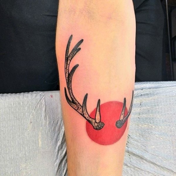 Cartoon style colored forearm tattoo of colored red circle and deer horns