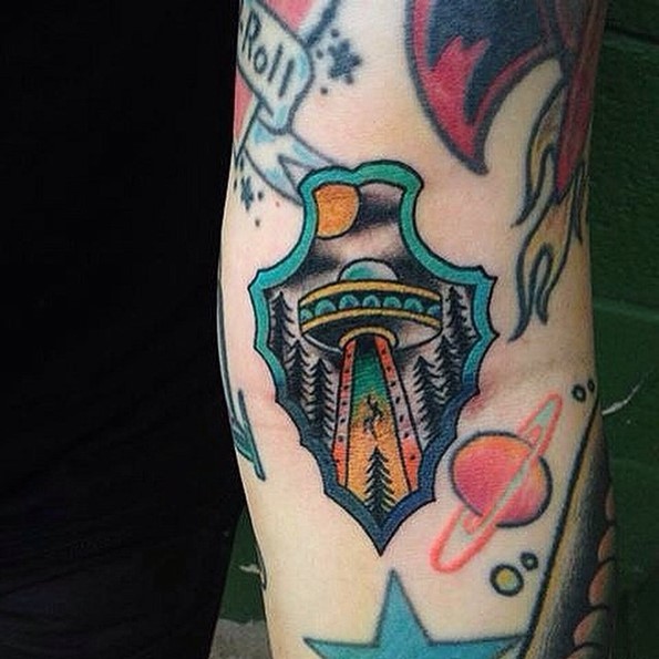 Cartoon style colored little antic weapon arm tattoo stylized with alien ship