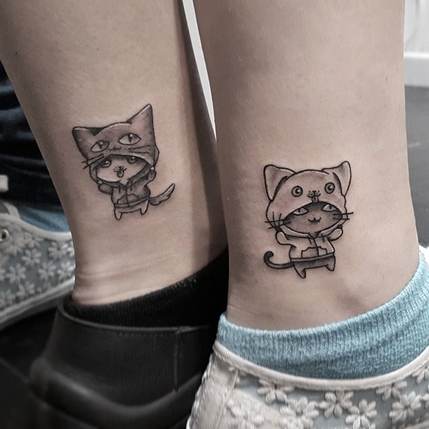 Cartoon style cute looking ankle tattoo of funny cats