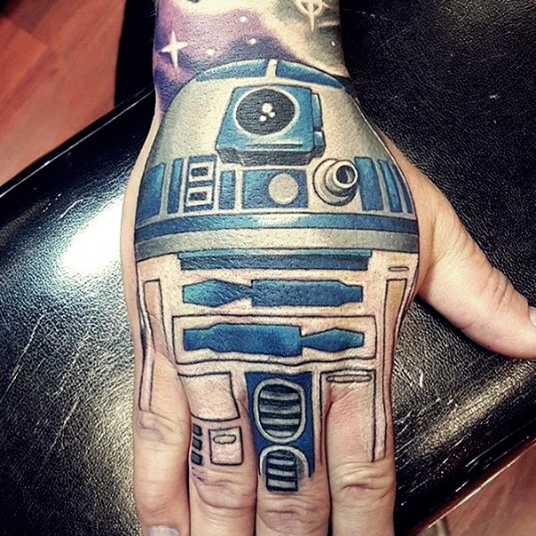 Cartoon Stil gefärbtes detailliertes Star Wars R2D2 Droid Tattoo an der Hand