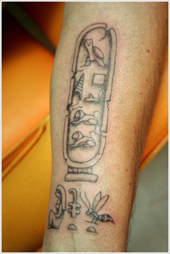 Tatuaje en el brazo de un cartucho con jeroglíficos egipcios.