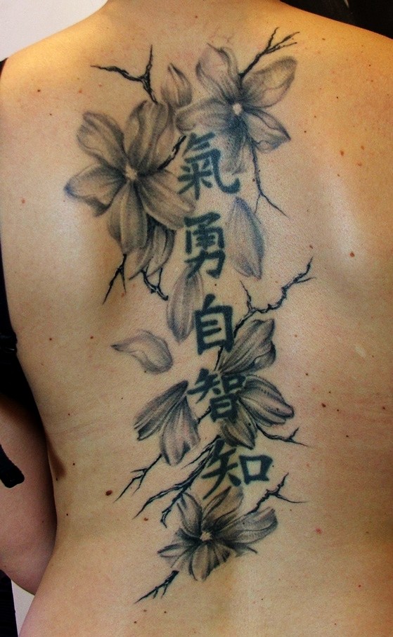 Tatuaje en la espalda, rama de flores de color gris y inscripción