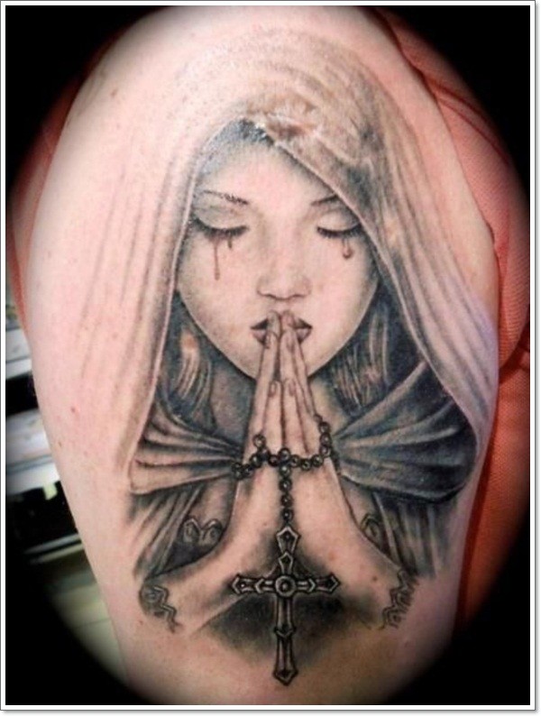 Christian themed colored praying and crying woman with cross tattoo on shoulder