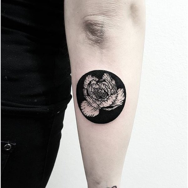 Circle shaped black ink forearm tattoo of small flower