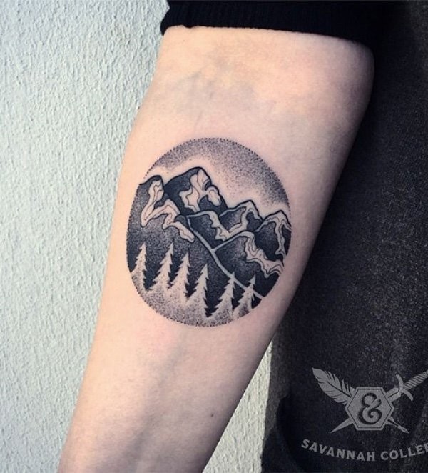 Circle shaped stippling style forearm tattoo of mountains with forest