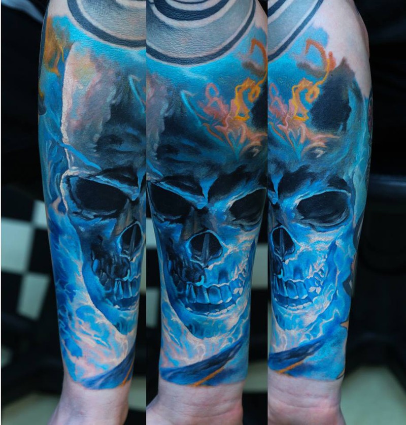 Colored accurate looking colored forearm tattoo of blue glowing skull