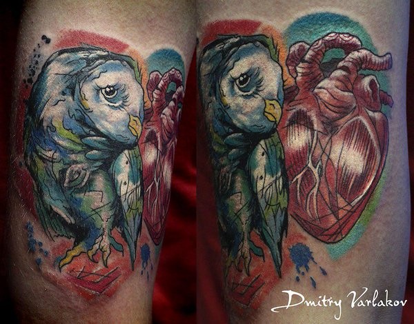 Colored biceps tattoo of owl with human heart