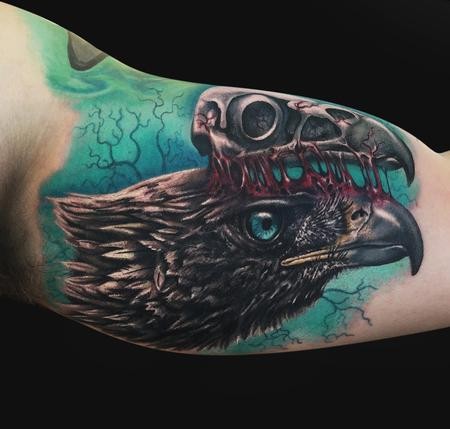 Colored cool looking biceps tattoo of crow with bird skull
