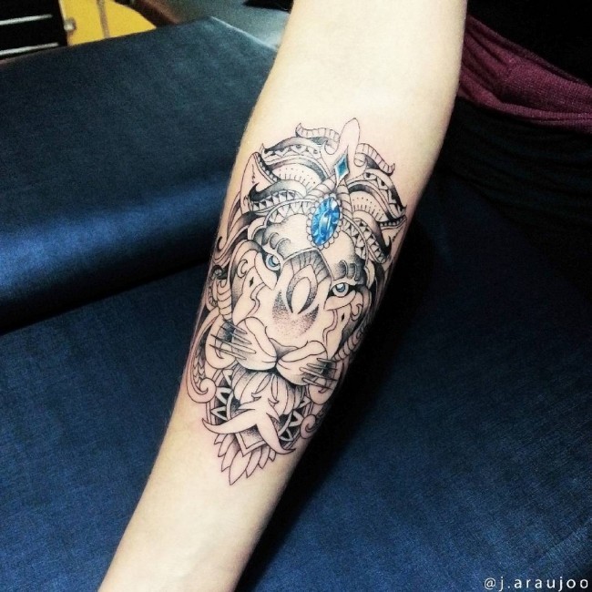Colored illustrative style forearm tattoo of lion with blue diamond