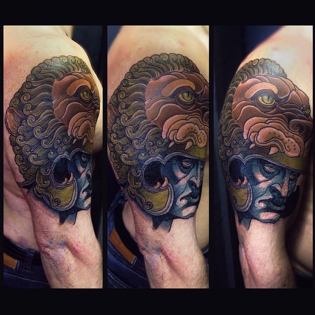 Colored illustrative style shoulder tattoo of human with lion helmet