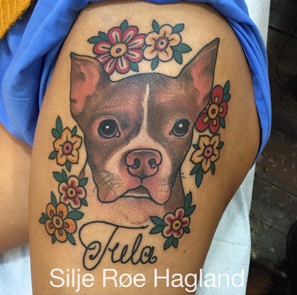 Colored illustrative style thigh tattoo of dog with flowers and lettering