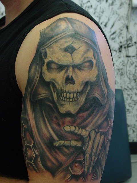Colored interesting looking illustrative style shoulder tattoo of creepy Grimm reaper