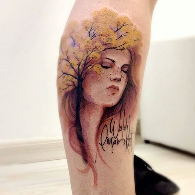 Colored leg tattoo of woman face with tree and lettering
